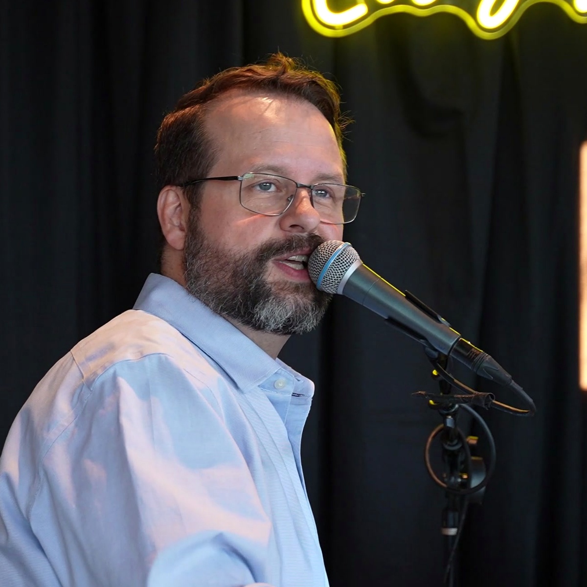 Elijah Hubbard singing into a microphone during a Midwest Dueling Pianos performance.
